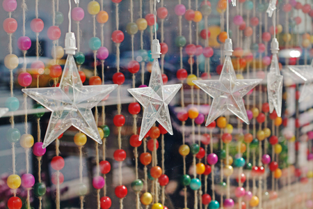 Garland in the form of large transparent stars hanging on a background of colorful beads on ropesの写真素材