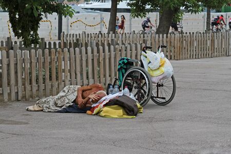 Barcelona, Spain - September 14, 2014: A homeless disabled person with a wheelchair sleeping on the asphalt in Barcelonaのeditorial素材