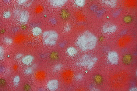 Multicolored spots on a pink painted decorative wall as background, texture