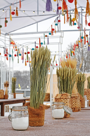 Green and dry rye in wicker pots and jars of salt standing on the table at the festivalの写真素材