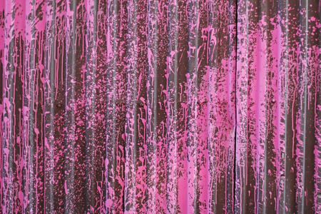 Black profiled sheet coating with pink splashes as background or textureの写真素材