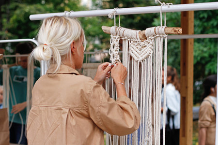 Moscow, Russia - August 18, 2019: Woman weaving macrame at the festival