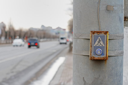 Dirty and old button on demand pedestrian crosswalk in the background of traffic