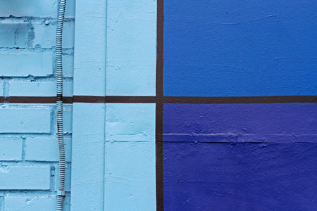 Colorful (black, light and dark blue) brick painted wall with pipe as background, texture