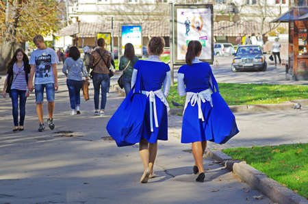 Lviv, Ukraine - October 19, 2012: Two young girl walking on the street with big bags advertising promotion in Lvivのeditorial素材