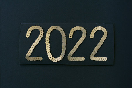2022 embroidered with golden sequins on black textured background as Happy New Year decoration