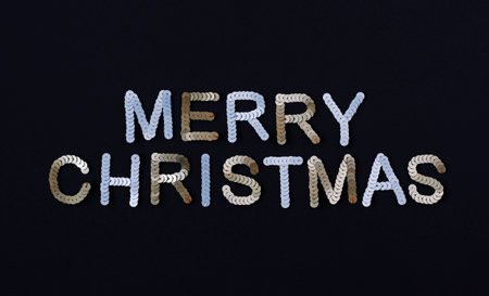 Inscription of Merry Christmas embroidered with silver and golden sequins on black textured...