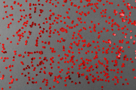 Scattered random red sequins in shape of hearts on black textured backgroundの写真素材