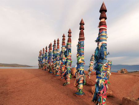 Vivid colored ribbons Hadak tied on posts of wish. Wooden ritual pillars. Sacred place of Buddhist shamans, Baikal, Russia. Mystical traditions of Asia.の写真素材