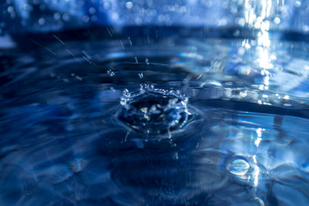 Water drop close-up macro photography. Blue water surface background.の写真素材