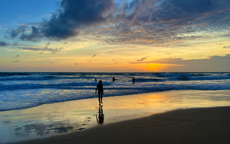Silhouette of a man walking on the beach at sunset.