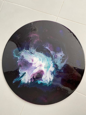 Black plate with blue and purple paint on a white background, close up