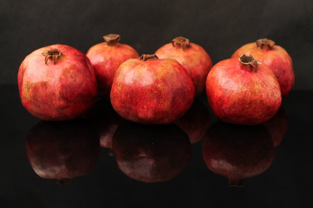 Ripe pomegranates on a black background with reflection.の写真素材