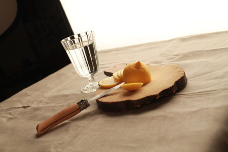 lemon and a glass of water on a wooden board with a knifeの写真素材