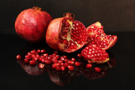 Ripe pomegranate fruit on a black background with reflectionの写真素材