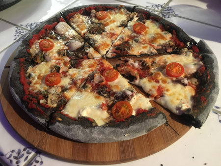 Pizza with cheese and cherry tomatoes on a round plate. Restaurantの写真素材