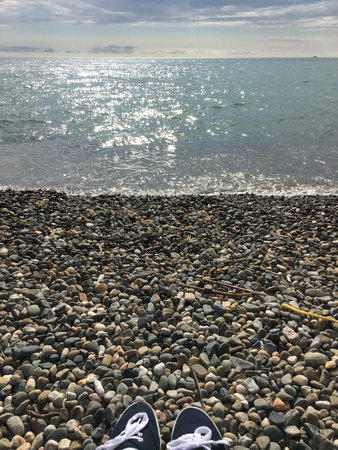 Selfie of sneakers on pebble beach with sea and sky