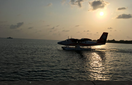 Tropical beach at sunset with a small plane in the foreground