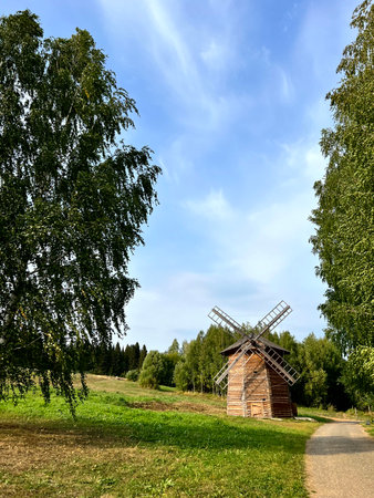 Old wooden windmill on the background of green forest and blue skyの写真素材