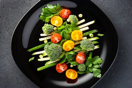 vegetable salad of cucumbers, broccoli, red and yellow cherry tomatoes with green onions and parsley.の写真素材