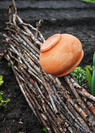 A clay pot on a wicker fence.の写真素材