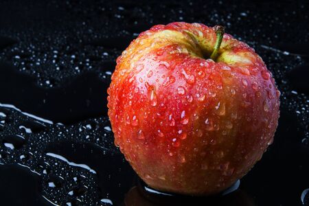 striped Apple with drops of rain, on the wet black glassの写真素材