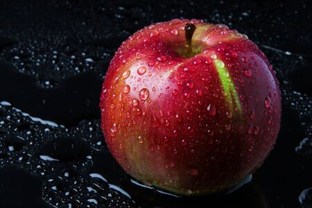 striped Apple with drops of rain, on the wet black glassの写真素材