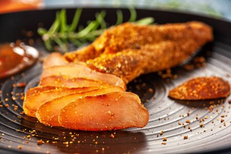 Chicken basturma with hot sauce on a black plateの写真素材