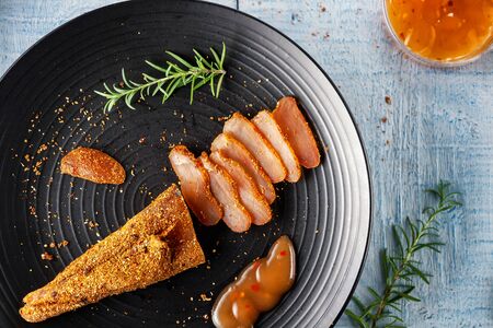 Chicken basturma with hot sauce on a black plateの写真素材