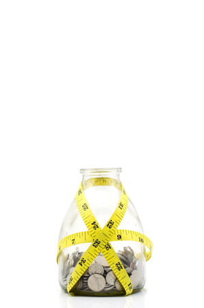 Tight financial budget concept with coins and measurement tape isolated on white backgroundの写真素材