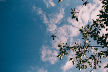 passenger plane flies in the blue sky with cloudsの写真素材