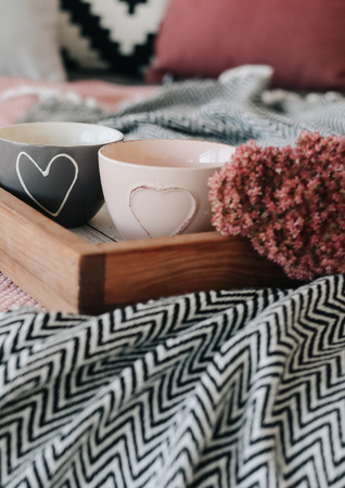 
two cups with a heart on the bed with flowers in the interiorの写真素材