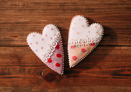 holiday cookies gift gingerbread in the form of two hearts with colored glaze on a wooden background in the centerの写真素材