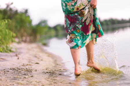 woman barefooted in a dress on the beach splashing waterの写真素材