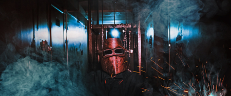 man worker mask sparks smoke dark roomの写真素材