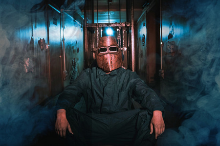 man in uniform and mask in a dark room with sparks smoke and light effectsの写真素材