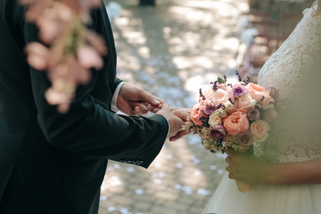 Wedding ceremony bride groom putting golden rings to finger of each otherの写真素材