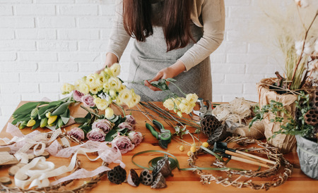 woman florist collects a bouquet decorates from different flowersの写真素材