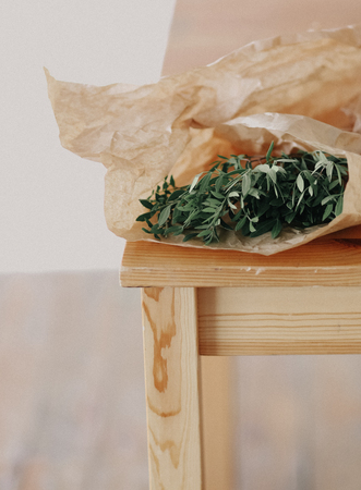 green eucalyptus leaves wrapped in decorative paper on a wooden chairの写真素材