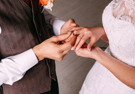 Wedding ceremony bride groom putting golden rings to finger of each otheの写真素材