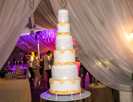 wedding cake six floors in the evening against a background dancing people on the tableの写真素材