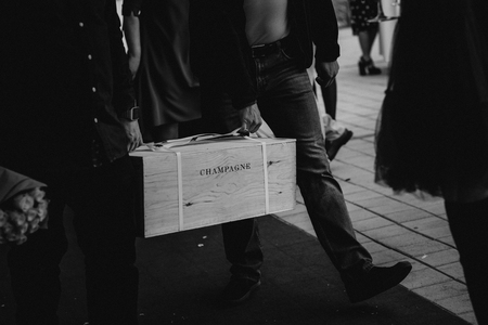 two men in the street carry a box with an inscription champagne and a bouquet of flowersの写真素材