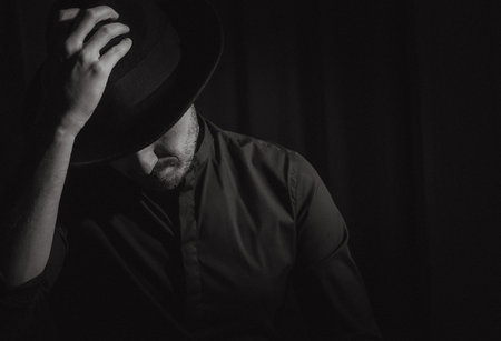man with a beard in a black hat bends his head