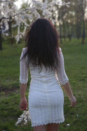 girl with a cherry blossom branch going back in the gardenの写真素材
