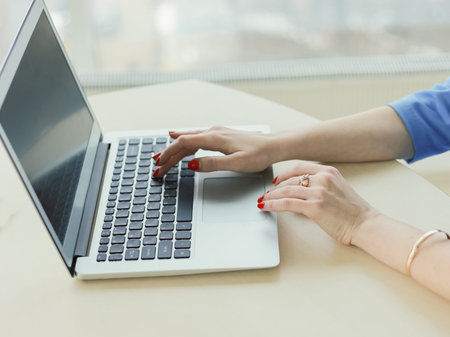 woman working in an office on a laptop hands and manicure