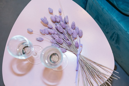 two glasses and lavender flowers on the table in the roomの写真素材