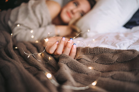 girl sleeps on the bed in the morning with a garland in her hand and dreams
