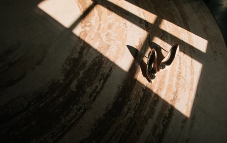 Womens shoes on the floor under the light with a shadow from the windowの写真素材