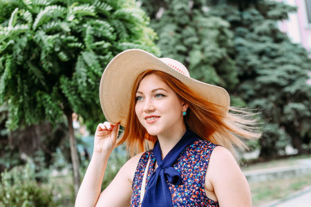 girl with a happy smile walking and holding her hat in the wind