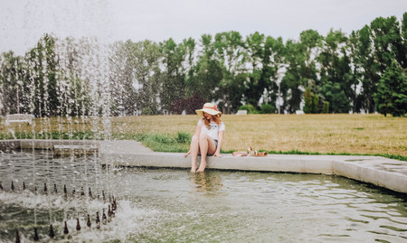 young girl wetting her feet in the pool with a fountainの写真素材